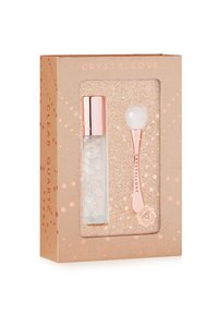Set di occhi in quarzo trasparente inserito in una scatola in oro rosa con accenti glitterati. Include un rullo trasparente e un applicatore sferico. Entrambi presentano superfici lisce e lucide.