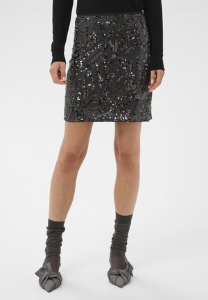 Falda mini negra con lentejuelas y acabado texturizado, que presenta un corte ajustado y dobladillo recto. Estilizada con calcetas grises transparentes y zapatos grises anudados.