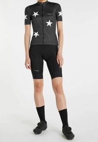Maillot de cyclisme noir avec des motifs d'étoiles blanches, à manches courtes et avec une fermeture éclair à l'avant, associé à un short rembourré noir et des chaussettes noires hautes.