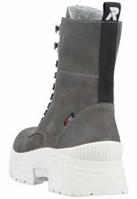 Botín de ante gris con suela gruesa blanca, que presenta acentos negros, diseño de cordones y una etiqueta lateral etiquetada.