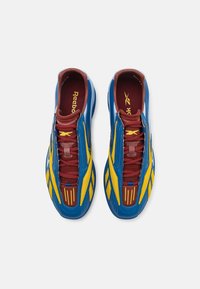 Blue athletic shoes with a sleek design, featuring yellow accents and maroon laces, textured upper, and a padded collar.