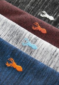 Fyra vikt t-shirts i olika färger: mörkblå, grå, vinröd och vit. Varje t-shirt har en liten broderad hummer i kontrasterande färger.