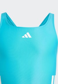 Débardeur de sport bleu clair avec de fines bretelles, arborant un logo blanc sur la poitrine. Fabriqué en matériau lisse et extensible avec une coupe ajustée.