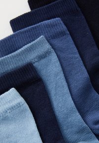 Calze di cotone in diverse tonalità di blu, che vanno da un azzurro chiaro a un blu navy scuro, presentano una texture a coste e motivi vari in un' disposizione impilata.