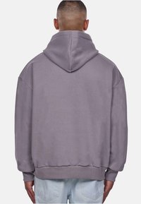 Hooded sweatshirt in soft, light purple fabric. Features dropped shoulders, ribbed cuffs, and a hem with a loose fit. Minimalist design.