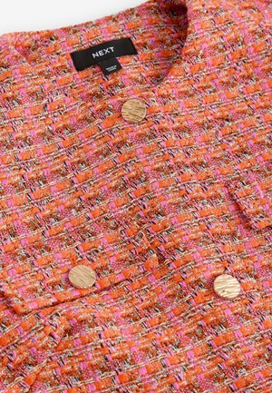 Orange and pink woven jacket with a textured fabric, featuring two round gold buttons and a collar. Label displays "NEXT".