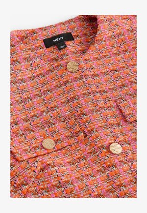 Oranžinė ir rožinė austinė striukė su tekstūruotu audiniu, su dviem apvaliais auksiniais mygtukais ir apykakle. Etiketėje nurodyta "NEXT".