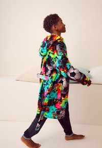 Bunter Kapuzenmantel mit abstrakten Mustern in Rot, Grün und Blau; verfügt über einen Gürtel, Taschen und eine weiche, plüschige Textur.