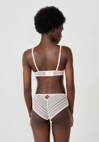 Light pink lingerie set featuring a lace bralette with adjustable straps and matching high-waisted panties with a diamond cutout and striped pattern.