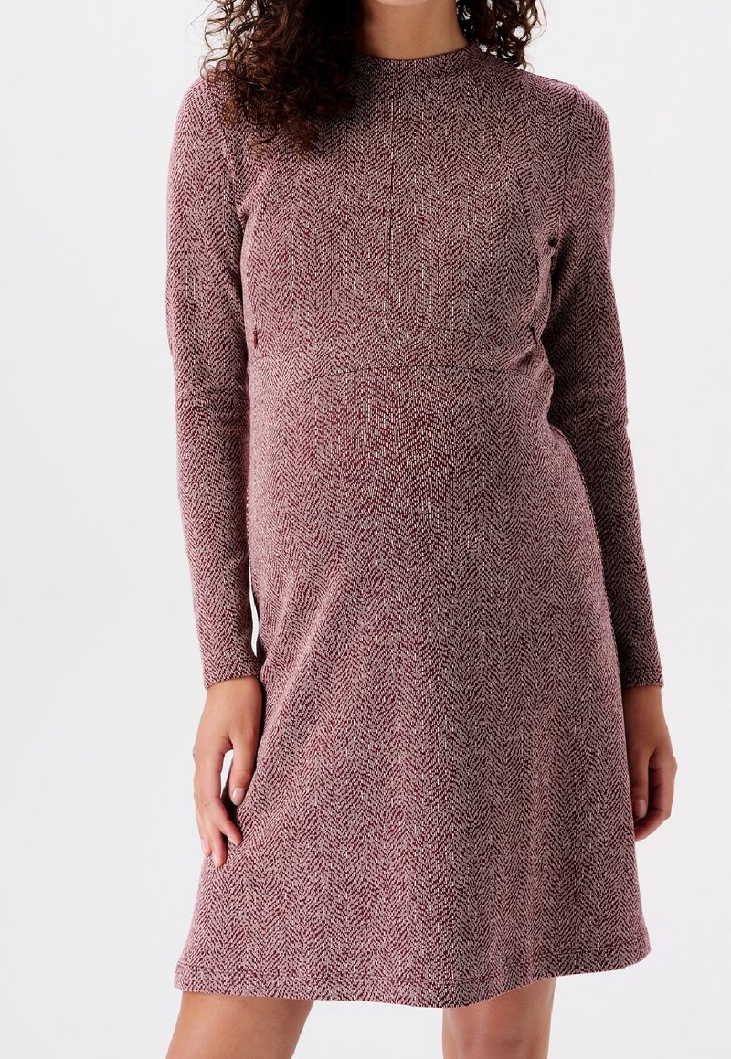 Langärmliges, kastanienbraunes Kleid mit Fischgrätstruktur, rundem Halsausschnitt und lockerer Passform. Mittellange, bis zur Oberschenkelmitte reichende Länge und weicher Stoff.