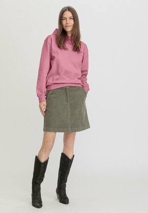 Roze sweatshirt met capuchon, olijfgroene corduroy rok en zwarte kniehoge laarzen. De outfit heeft een casual ontwerp met een zachte textuur.