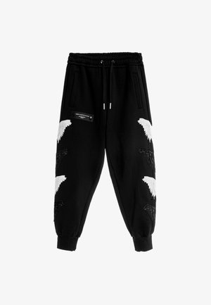 Pantalones de chándal negros con cintura elástica, que presentan diseños de alas bordados en blanco y una pequeña etiqueta negra con herrajes plateados en el lateral.