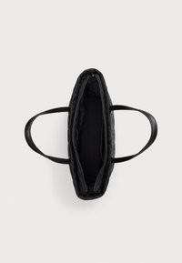 Crna prešivena torba za nošenje s dva ručka, otvorenim vrhom i glatkom unutarnjom podstavom. Ima zatvarač na patent i minimalistički dizajn.