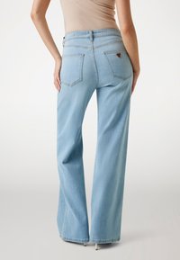 Heledad sinised laiad püksid kõrge vööiga, millel on kaks tagakotti ja kontrastõmblused. Pehme denimpind sujuva tekstuuriga.