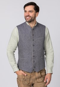 Blaugraue Weste mit Rundhalsausschnitt, silbernen Knöpfen, zwei Taschen und Kontrastnähten, getragen über einem hellgrünen Langarmhemd.