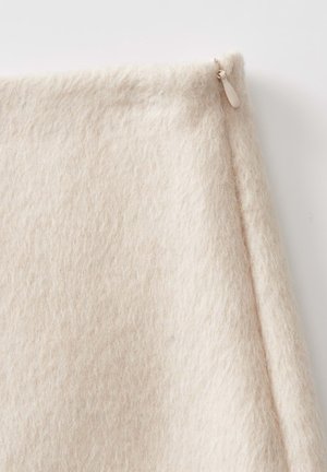 Lichtbeige, zacht, gestructureerde stof met een lichte plumbo. Kenmerkt zich door een discrete ritsaccent aan één rand.