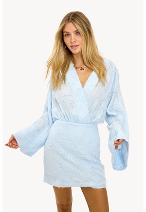 Robe enveloppante bleu clair en tissu texturé, avec de longues manches cloche et une taille cintrée. Présente des motifs floraux et une apparence douce et superposée.