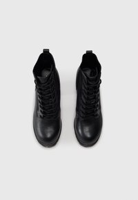 Black leather ankle boots with a smooth finish, featuring a lace-up design and elastic detailing at the collar for flexible fit.
