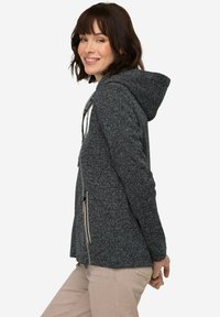 Huvtröja i mörk marinblå med en fläckig textur. Utrustad med dragkedjefickor på sidorna och dragsnören för justerbar passform. Mjuk och bekväm tyg.