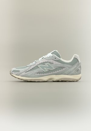 Šviesiai pilka ir balta „New Balance“ sportinė avalynė iš tinklelio ir zomšos medžiagų, suvarstoma raišteliais ir turi tekstūruotą gumos pado dalį.