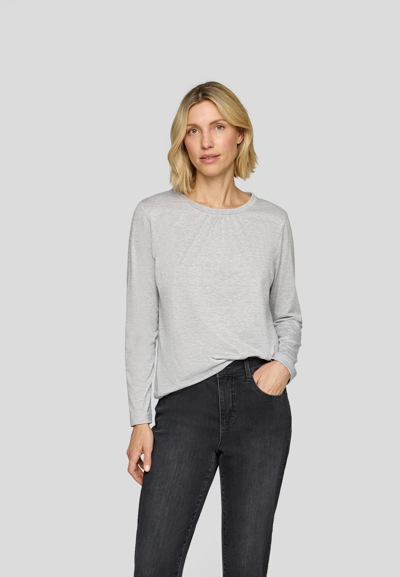 Light grey long-sleeve top with a round neckline and gathered detail at the front, paired with black jeans. Soft fabric, relaxed fit.