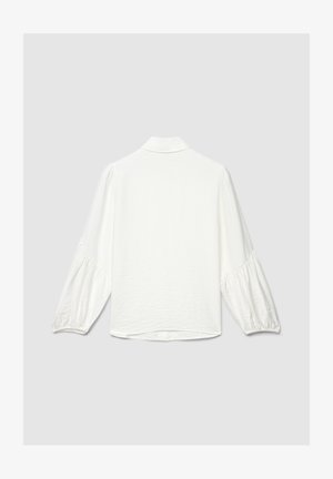 Blusa bianca a maniche lunghe con maniche a sbuffo raccolte e un piccolo colletto, mostrata di schiena su uno sfondo grigio chiaro uniforme.