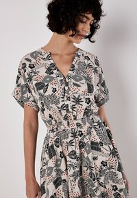 Kurzes Kleid aus leichtem Stoff mit einem schwarz-korallenfarbigen Blumenmuster, V-Ausschnitt und elastischem Bund für eine schmeichelhafte Passform.