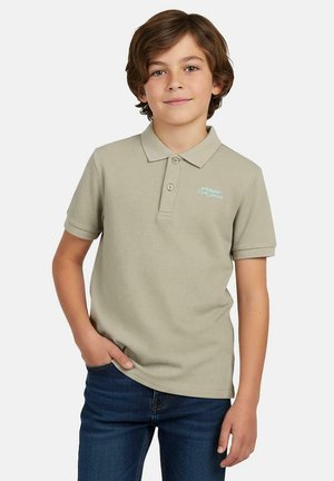 Polo met korte mouwen van lichtbruine katoenstof, voorzien van een kraag en een subtiel aqua logo op de borst. Draagt bij een spijkerbroek.