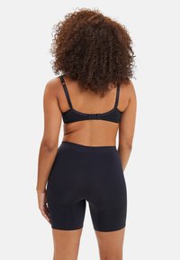 Bragas ajustadas negras con una textura suave, cintura alta y longitud hasta el muslo. Tirantes ajustables y cierre de gancho en la parte posterior.