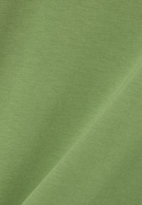 Tela de algodón verde brillante con una textura suave, que presenta un ligero brillo y un tejido uniforme y consistente. Ideal para ropa o accesorios.