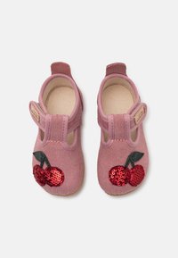 Rozā auduma kurpes ar teksturētu virsmu, kurām ir sarkano un zaļo pērlīšu ķiršu dizains. Aizvērtā purngala un ar Velcro siksniņu.