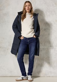 Laivastonsininen pusakka, kerma valkoista nyöri neuletta, tummansiniset farkut, valkoiset lenkkarit mustilla raidoilla. Sileät materiaalit ja kerroksellinen muotoilu.