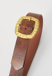 Brown leather belt with a textured finish, featuring a large, gold, square, hammered buckle. Smooth edges and a tapered end.