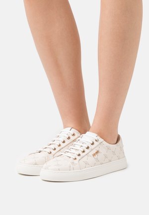 Beige Sneakers mit einem strukturierten Muster, weißen Schnürsenkeln und goldenen Ösen. Die Sohle ist weiß und das Obermaterial hat einen dezenten Glanz.