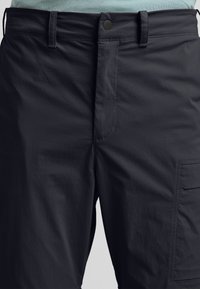 Pantaloni cargo grigio scuro con una texture liscia e leggera. Presentano una zip frontale, chiusura con bottone e una grande tasca laterale.