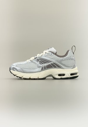Chaussure de course Nike blanche et grise avec tige en mesh, semelle amortie, unité d'air visible et languette de tirage sur fond neutre.