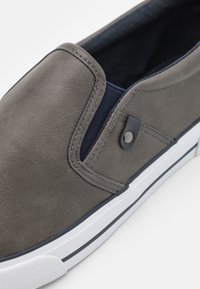 Grau Faux-Leder Schlupfschuh mit navyblauem elastischen Einsatz, weißer Gummisohle und schwarzem Kontrastnähten. Verfügt über eine abgerundete Zehenpartie und eine glatte Textur.