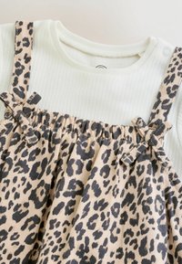 Hellgrünes, geripptes Oberteil kombiniert mit einem beigefarbenen Leopardenmuster-Kleid, ausgestattet mit verstellbaren Trägern und geraffter Taille für eine lockere Passform.