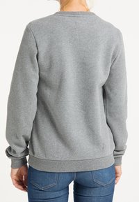 Grijze sweatshirt met een ronde hals, geribbelde manchetten en zoom. Zacht fleece-materiaal, comfortabele pasvorm, getoond van achteren met een blauwe jeans.