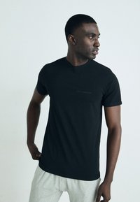 Juoda trumpa rankovė t-shirta, pagaminta iš švelnios medvilnės, su apvalia iškirpte, priekyje yra subtilus "KARL LAGERFELD" logotipas.