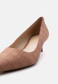 Καφέ μυτερό παπούτσι χαμηλού τακουνιού από σουέντ με ανάγλυφο σχέδιο κροκοδείλου, εμφανιζόμενο από μπροστινή πλευρά σε λευκό φόντο.