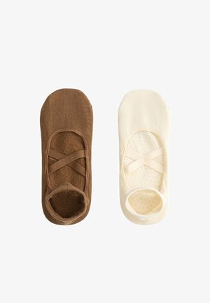 Une chaussette invisible marron et une crème avec des brides élastiques croisées, présentées côte à côte sur un fond blanc.