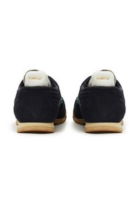 Marineblaues Wildleder Sneaker mit grünen Akzenten, beiger Gummisohle und hellfarbener Fersenschlaufe mit geprägtem Markenlogo.