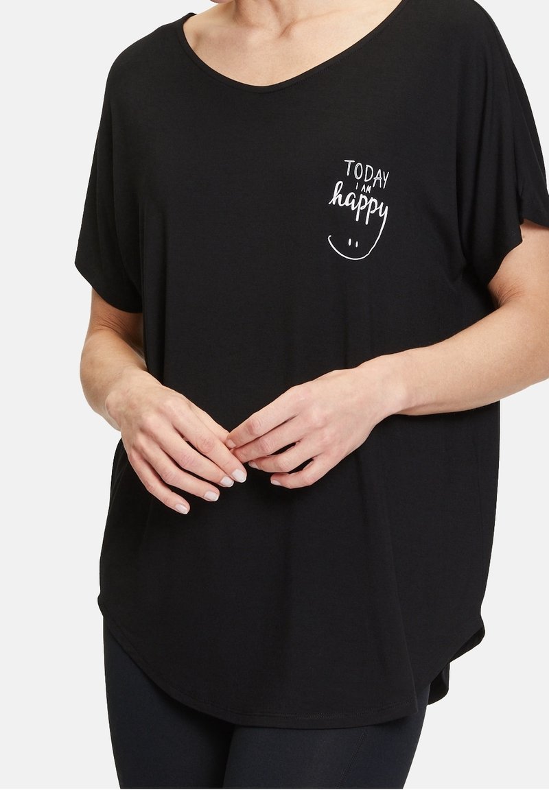 Svart kortärmad t-shirt med lös passform, rund halsringning och vit tryckt text "IDAG ÄR JAG glad" med en smiley.