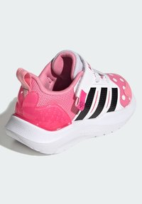 Baskets pour enfants avec tulle rose et blanc, rayures noires, pois, et une semelle en caoutchouc texturée avec un accent rose ludique au talon.