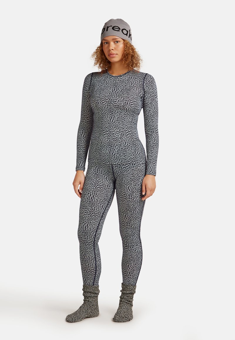Full-body thermal suit in black and white pattern, made from stretchy, textured material. Includes matching knitted socks and beanie.