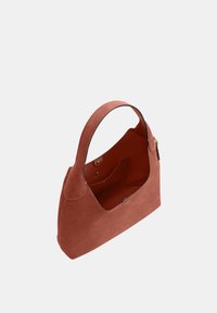 Petit sac à main en daim couleur rouille avec une seule sangle, ouverture supérieure avec boutons-pression, et une poche latérale intérieure.