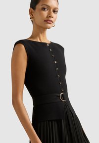 Must mustriga kleit, millel on sobiv kehaosa, kuldse tooniga nupud ja vöödiga talje ümmarguse pandlaga, voolates plisseeritud seeliku suunas.