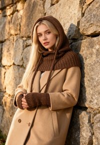Palton bej din lână cu glugă tricotată texturată maro și mănuși fără degete. Combinația de culori și materiale oferă căldură și protecție.