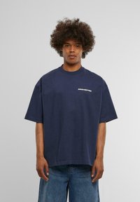 Marineblå bomulds oversized t-shirt med rund hals og korte ærmer, der pryder ordene "PROHIBERET" med hvid skrift на brystet.